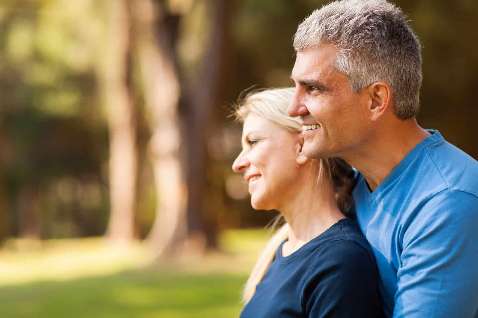 loving middle aged husband with wife outdoors looking forward